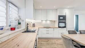 Eine moderne Küche mit weißen Schränken, einer Holzauskładung und einem eingebauten Backofen.