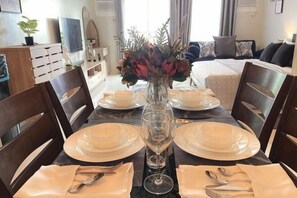 A dining table set with plates, cutlery, and a vase of flowers. - David & Jens 's Suite in Camella Manors Verdant (Puerto Princesa)