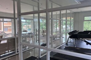 A spacious room with large windows, a piano, and a treadmill. - David & Jens 's Suite in Camella Manors Verdant (Puerto Princesa)