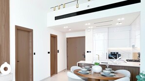 A modern kitchen with white cabinets, a central island with seating, and a dining area with a round table and chairs.