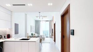A modern kitchen with a central island, a dining area with a view, and a hallway leading to a door.