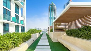 A modern building with a green artificial turf pathway, white steps, and planter boxes with greenery.