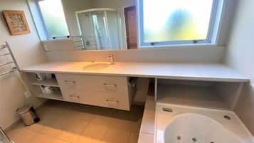 A modern bathroom with a large window, a bathtub, and a vanity with drawers.