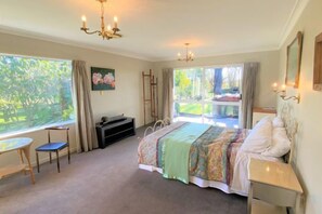 A bedroom with a bed, a desk, and a window with a view of greenery. - Calm Swan Villa (Christchurch)