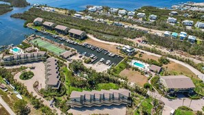 An aerial view of a coastal resort with multiple buildings, a marina, and a large body of water.