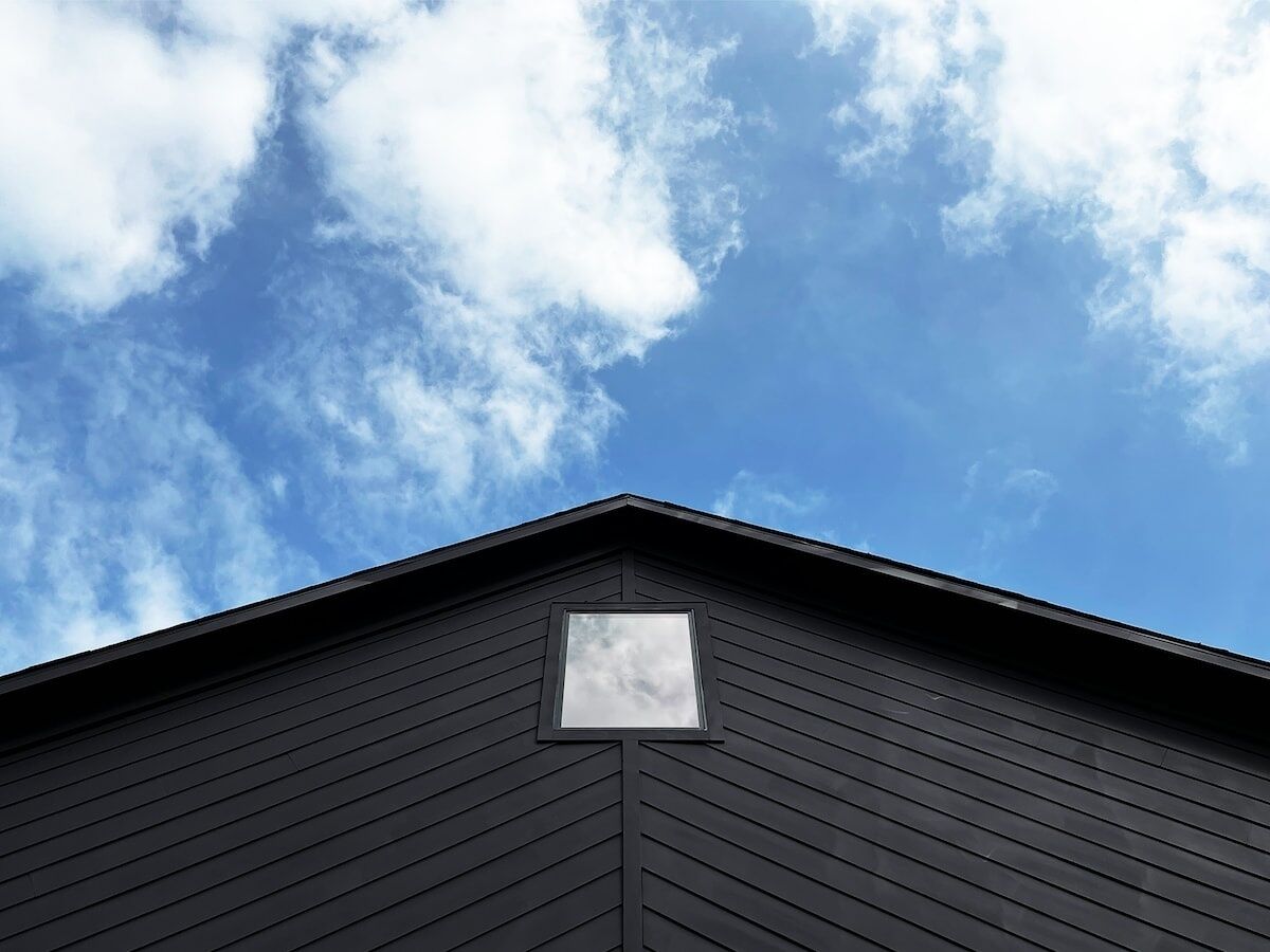 A building with a dark exterior and a small window at the peak of the roof.