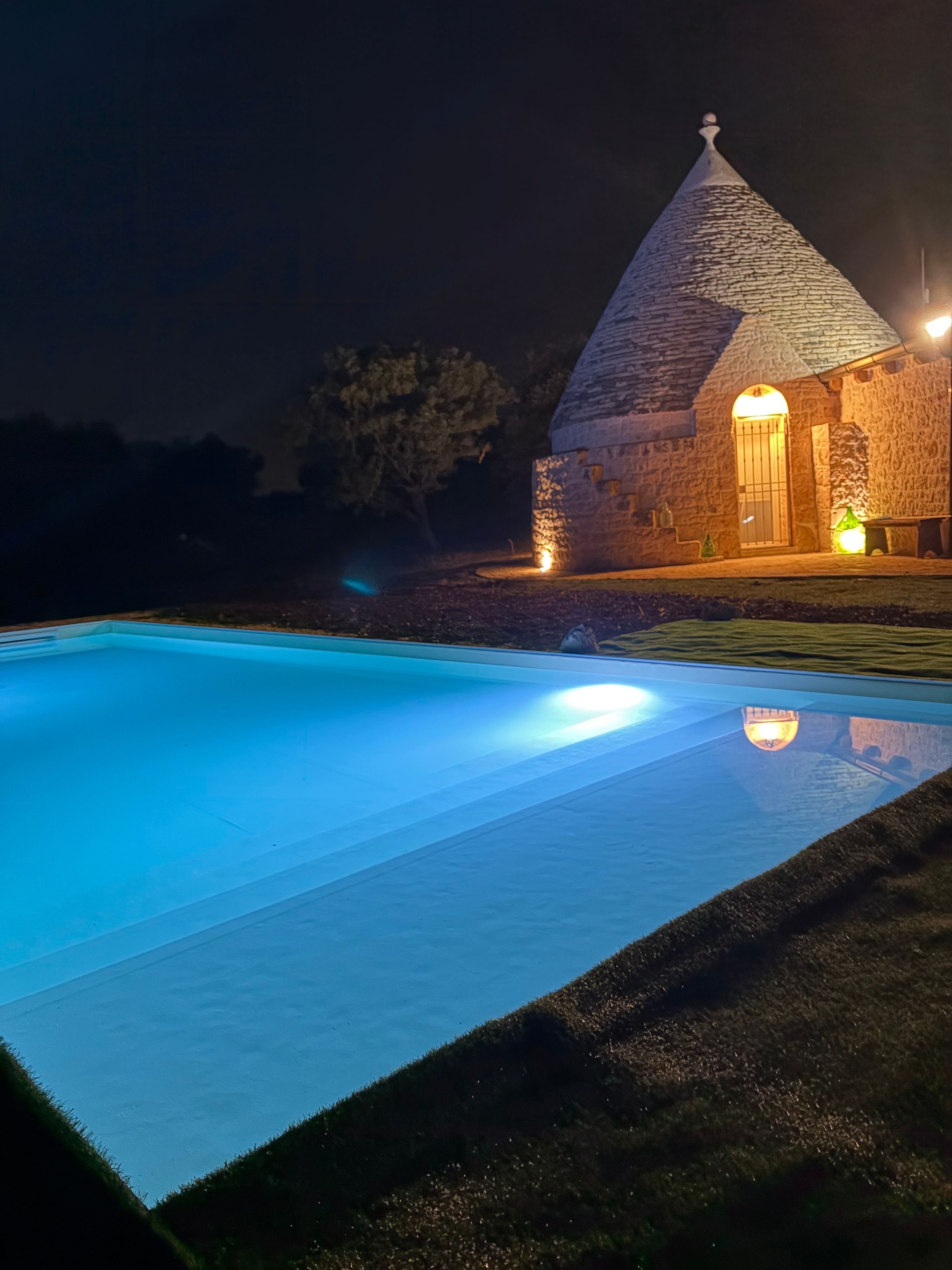 Ein Steinhaus mit einem Kegeldach und einem Pool davor.