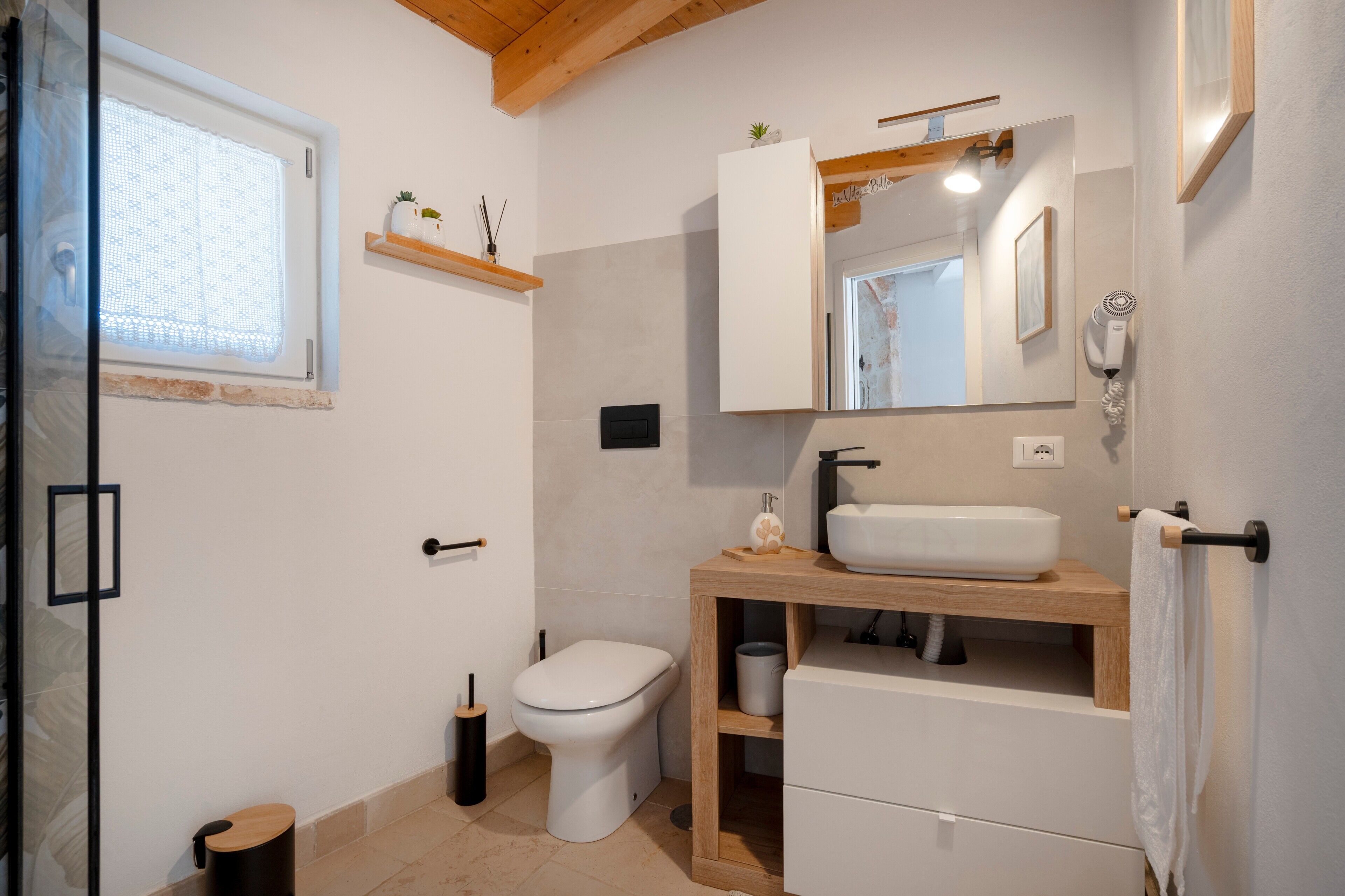 Een moderne badkamer met toilet, wastafel, spiegel en handdoekhouder.