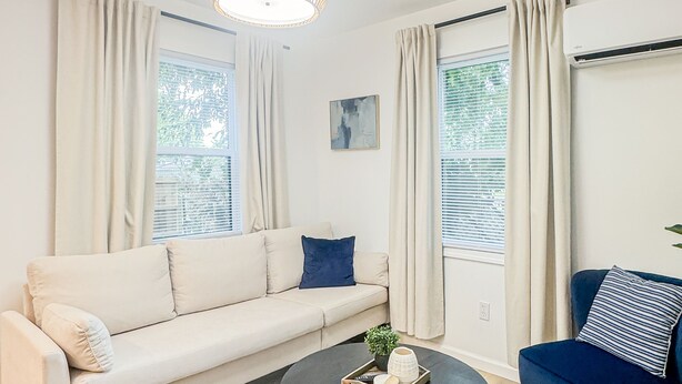 Una sala de estar moderna con un sofá, una mesa de centro redonda y un sillón azul.
