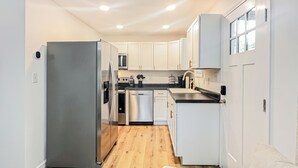 Una cocina moderna con armarios blancos, electrodomésticos de acero inoxidable y piso de madera.