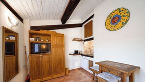 A kitchen with wooden cabinets, a TV, and a dining table with chairs.
