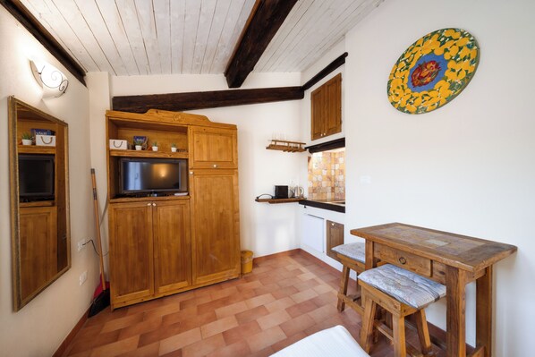 Una cocina con armarios de madera, un televisor y una mesa de comedor con sillas.