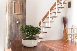 A potted plant on a wooden table near a staircase.