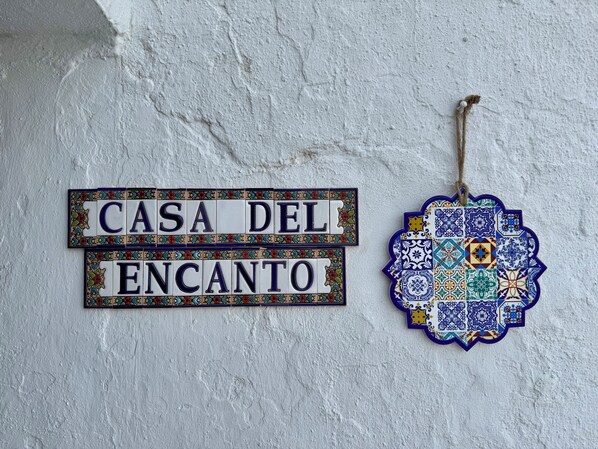 A sign reading "CASA DEL ENCANTO" on a textured wall.