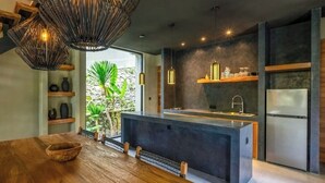 Een moderne keuken met een centraal eiland, hanglampen en een stenen muur.