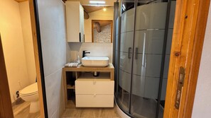 A compact bathroom with a white sink, a toilet, and a glass shower enclosure. - Bed and Breakfast, Les Rozières Family Suite in the Marais Poitevin (Le Bourdet)