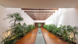 Un interior moderno con piso de madera, una fuente central y plantas a ambos lados.