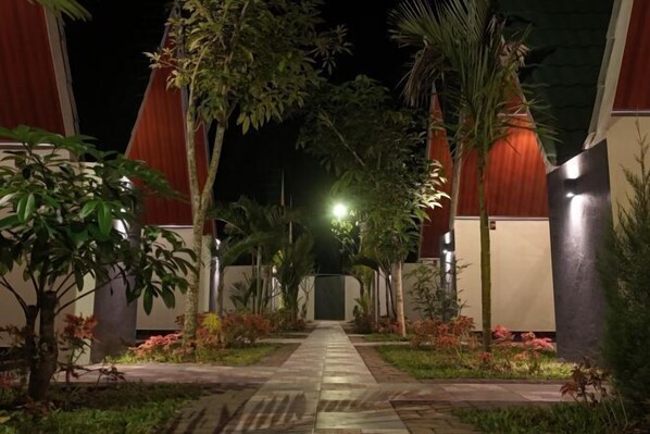 Un sendero conduce a un edificio de diseño moderno, rodeado de vegetación y palmeras.