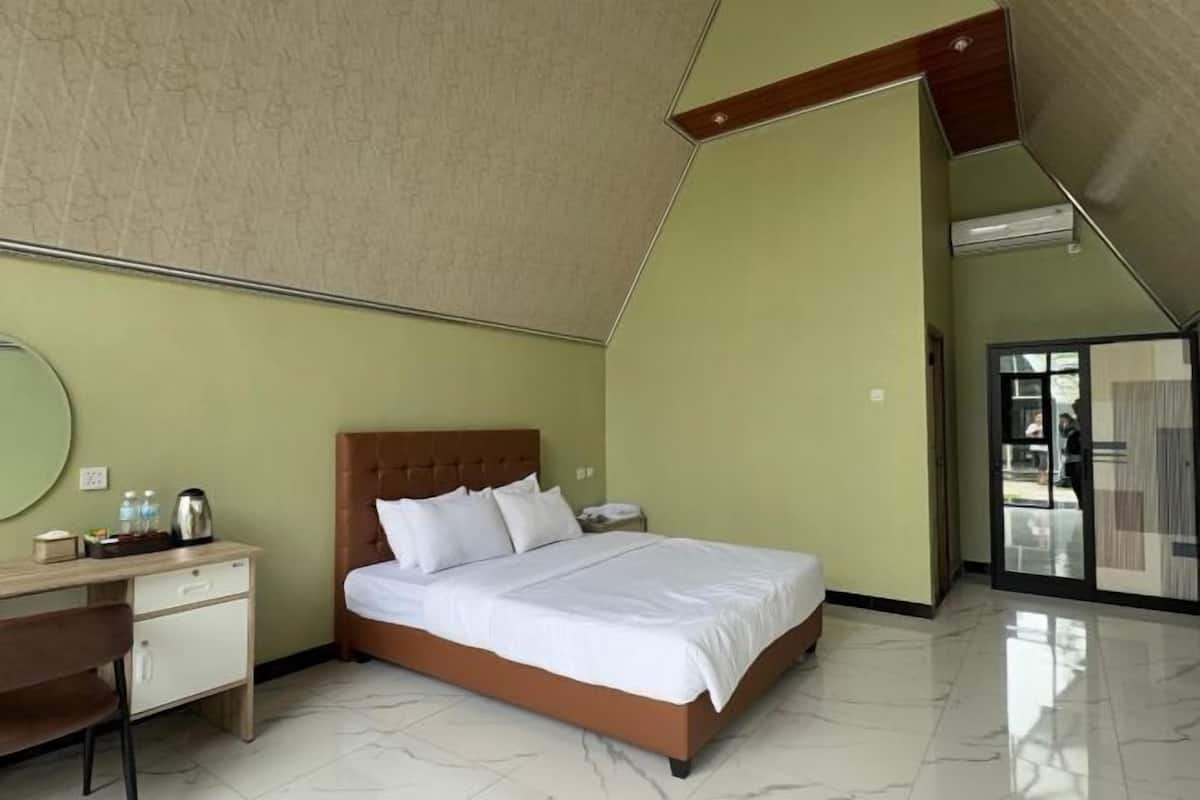 A modern hotel room with a bed, a desk, and a mirror.