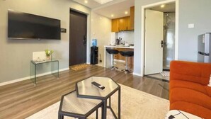 A modern living room with a glass coffee table, a sofa, and a TV mounted on the wall. - Luxe haven in Kilimani with Infinity Pool & Gym (Nairobi)