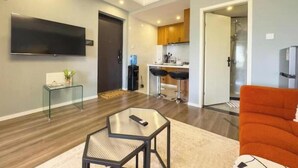A modern living room with a glass coffee table, a sofa, and a TV mounted on the wall.