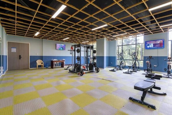 A gym with a checkered floor, weightlifting equipment, and cardio machines.