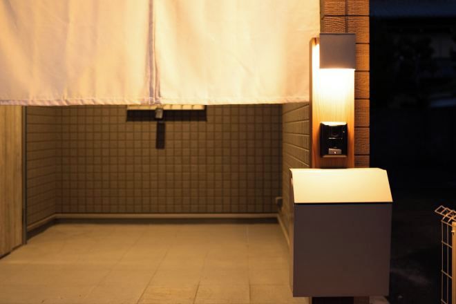 Des toilettes avec un mur carrelé, une serviette suspendue et un luminaire fixé au mur.