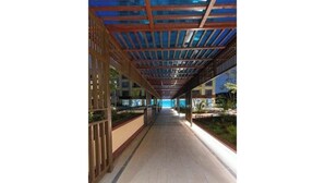 A corridor with a wooden ceiling and glass panels, leading to a pool area.