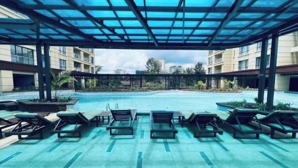 A covered swimming pool with lounge chairs and a view of surrounding buildings.