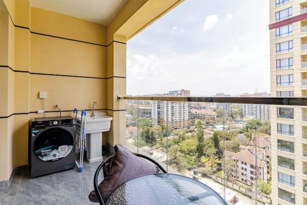 Ein Balkon mit Waschmaschine, Spüle und Blick auf die Stadtlandschaft.