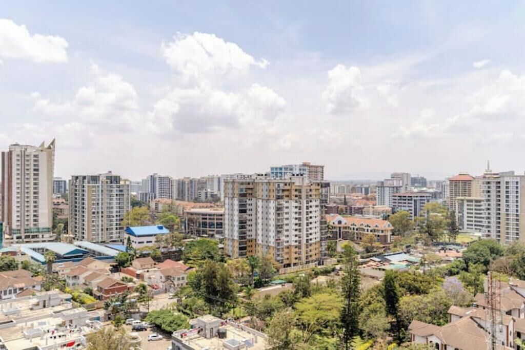 Un paysage urbain avec de hauts immeubles, un mélange de bâtiments résidentiels et commerciaux, et un ciel dégagé.