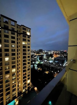 A high-rise building with multiple floors and windows, viewed from a balcony at dusk. - Lucullan spacious/ pool/gym/kingbed at yaya center (Nairobi)