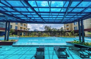 Una piscina coperta con lettini, circondata da edifici e vegetazione.