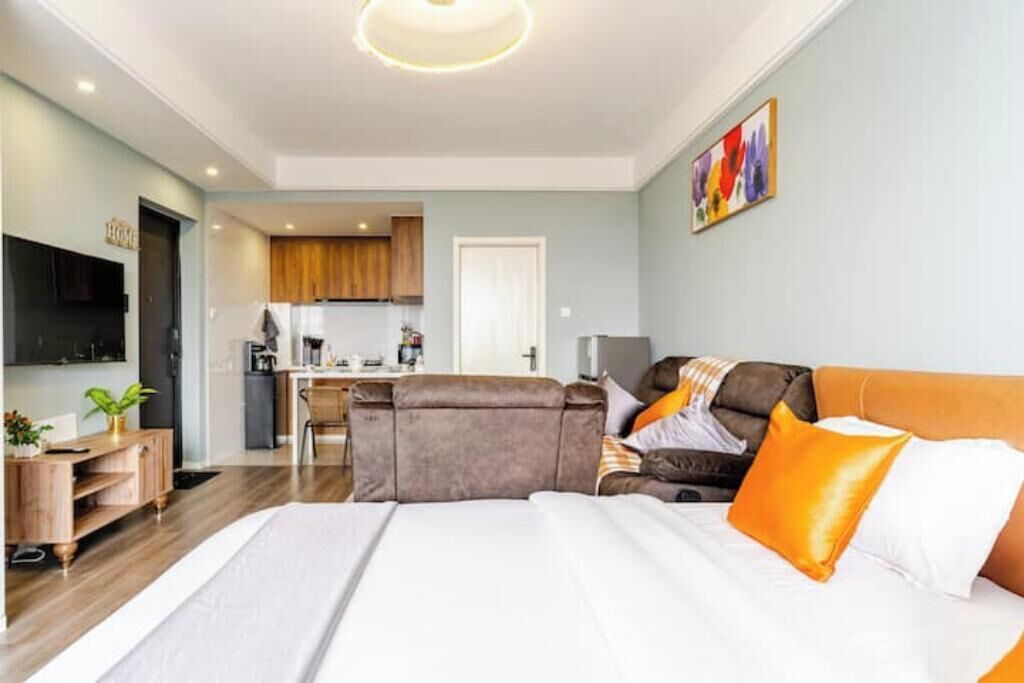 Una habitación de hotel moderna con una cama grande, un sofá, un comedor y un televisor.