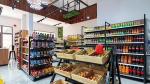 A grocery store interior with wooden crates of fruits and vegetables, shelves stocked with beverages, and a clean, modern design.