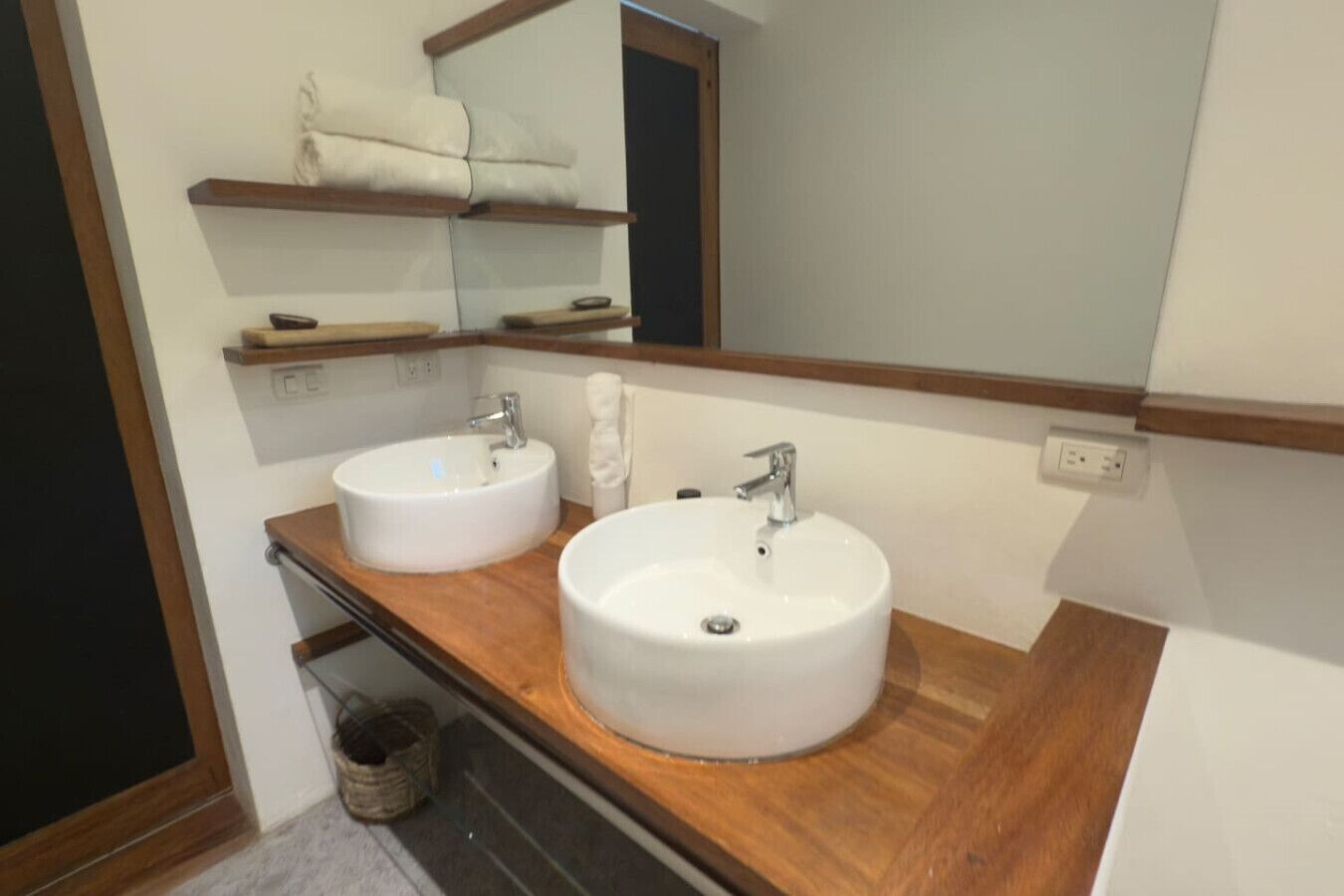 A bathroom with two white sinks, a wooden countertop, a mirror, and a towel rack above the sinks.