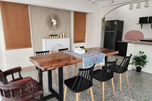 A compact dining area with a wooden table, black chairs, and a small kitchen area with a refrigerator and microwave. - Sova Vcay Pool Villa (Ban Chang)