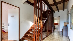 Uma escadaria com corrimãos de madeira, uma porta branca com a inscrição 'CABINET' e piso de azulejos.