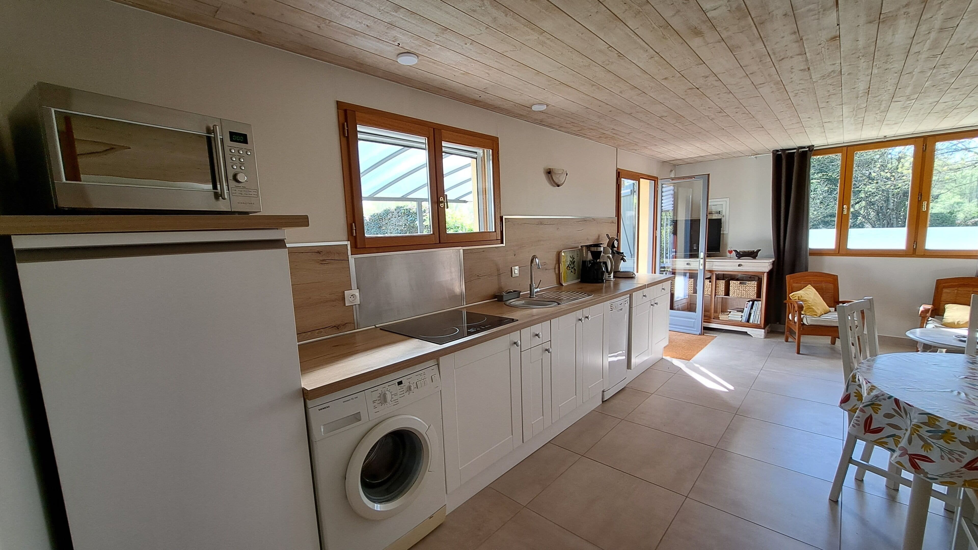 A kitchen with a washing machine, a microwave, and a sink.