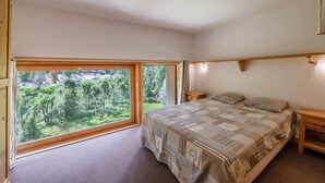 Ein Schlafzimmer mit großem Fenster, einem Bett und einem Nachttisch.
