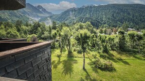 Blick vom Balkon auf eine gebirgige Landschaft mit dichten Wäldern und blauem Himmel.