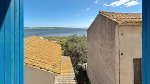 A coastal view with a clear sky, a body of water, and buildings with tiled roofs. - Charming house with terrace and breathtaking views (Bages)