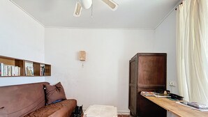 A compact living space with a brown sofa, a small white table, a wooden cabinet, and a ceiling fan. - Charming house with terrace and breathtaking views (Bages)