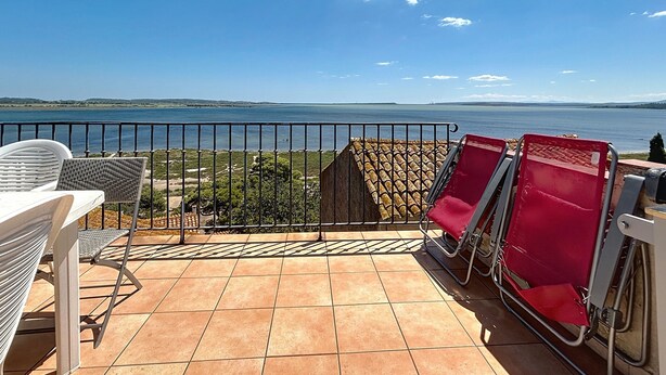 A terrace with a view of a large body of water, a railing, and several chairs. - Charming house with terrace and breathtaking views (Bages)