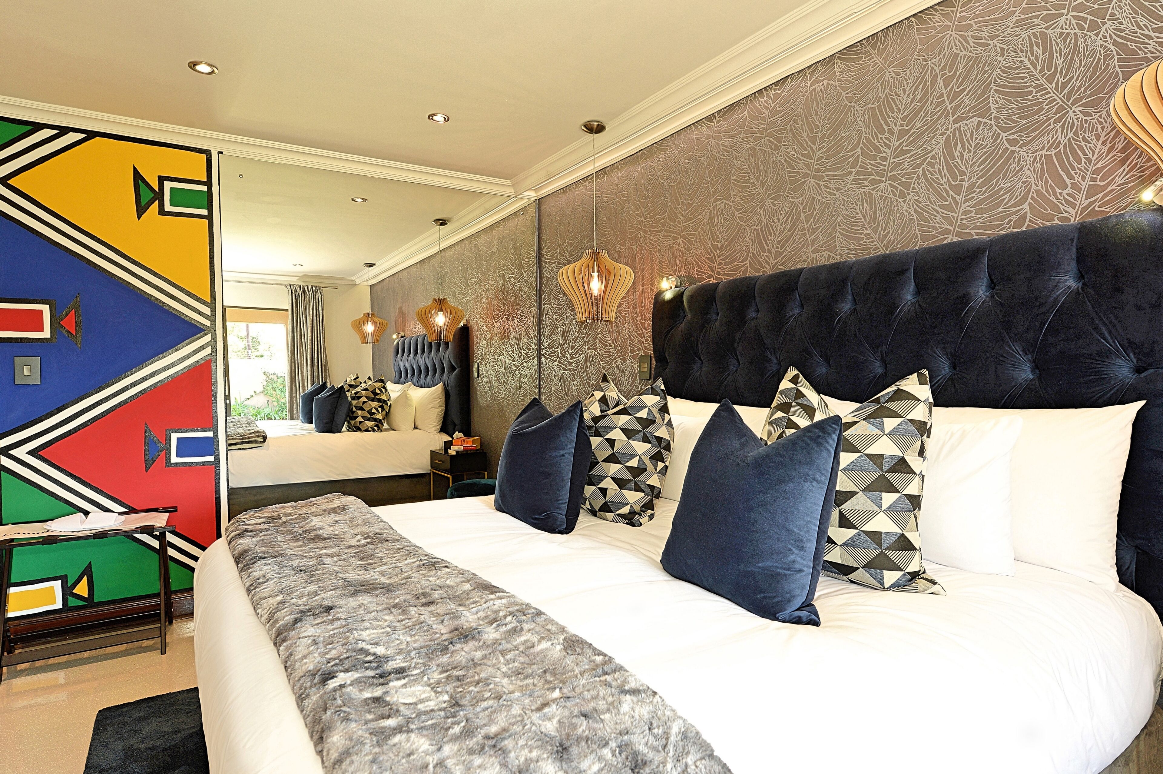 A modern hotel room with a large bed, patterned wallpaper, and a unique geometric wall design.