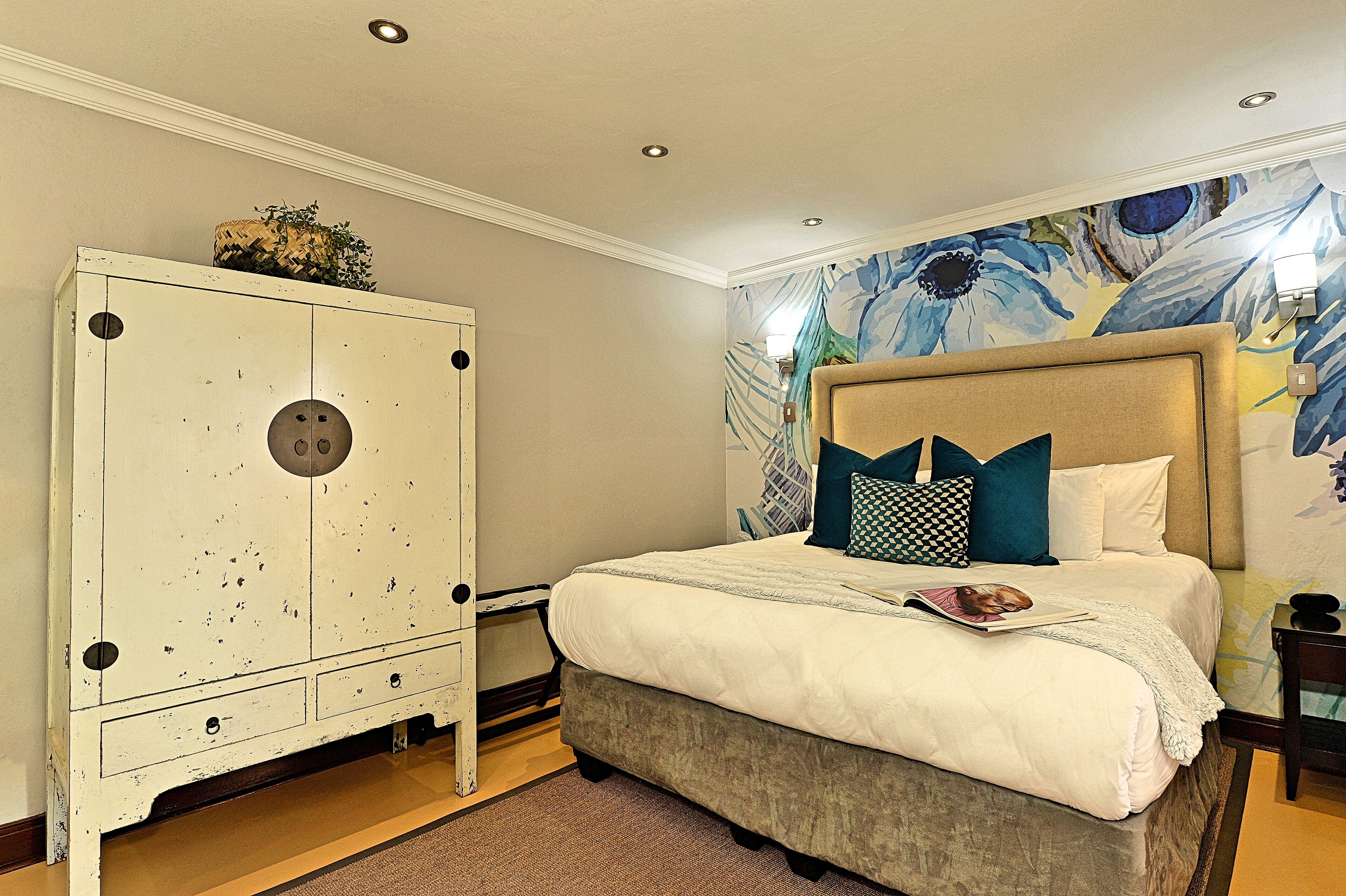 Un dormitorio con cama, un armario grande y un mural floral en la pared.