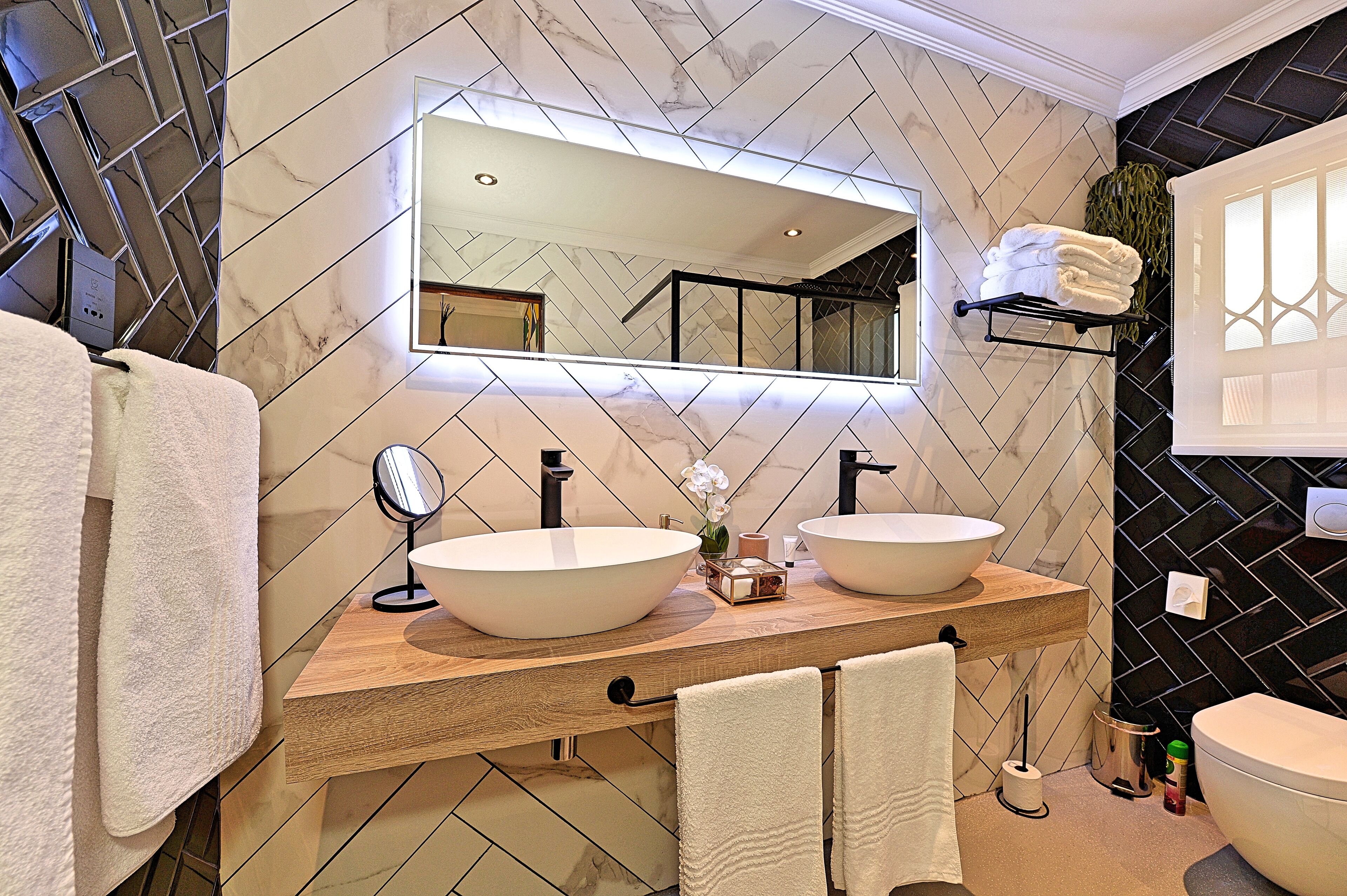 A modern bathroom with two large sinks, a mirror, and a wooden vanity.