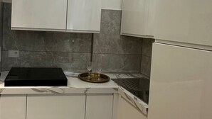 A kitchen with white cabinets, a black countertop, and a stainless steel sink. - Alloggio Turistico King Plaza (Rome)
