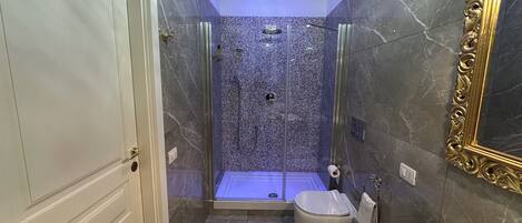 A modern bathroom with a glass-enclosed shower, a white toilet, and a large sink.