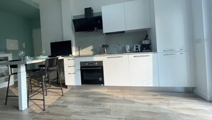 Una cocina moderna con armarios blancos, horno empotrado y comedor con mesa y sillas.
